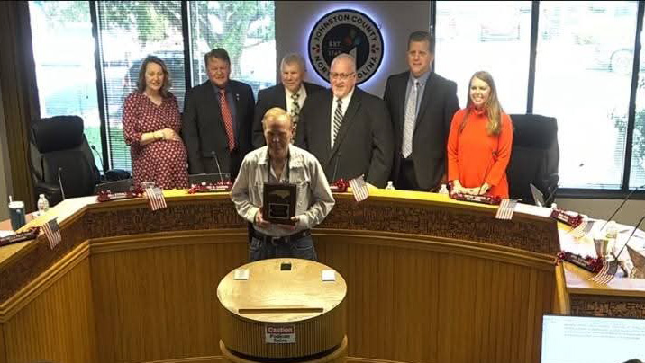 Charles Pender holding award, standing with the Board of Commissioners